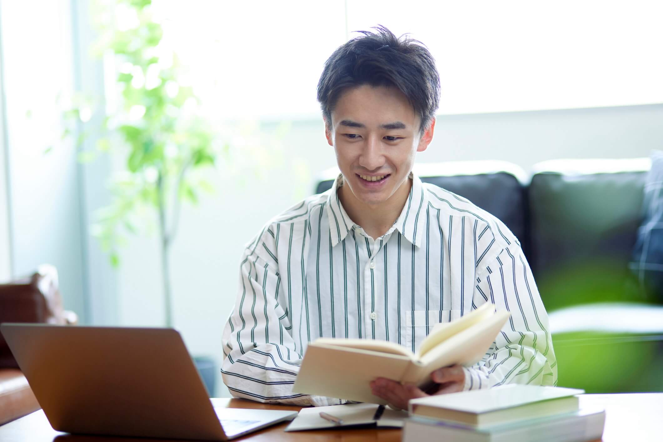 画像：男性がオンライン教材とテキストを使って学習しています。